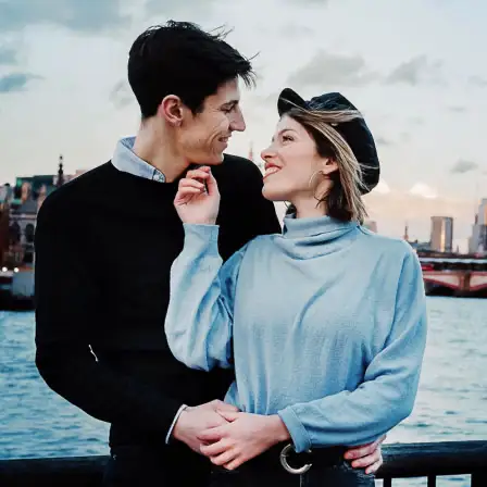 Loving couple embracing on a cold afternoon by the River Thames with the backdrop of the city of London.